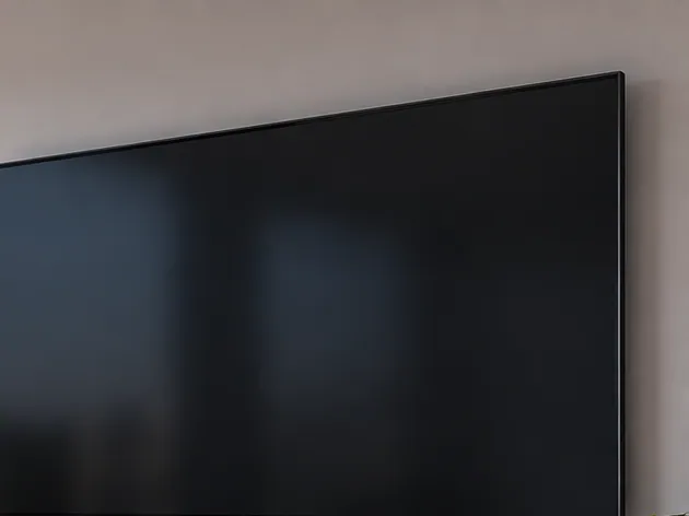 Un grande display professionale spento, montato a parete in una sala riunioni.